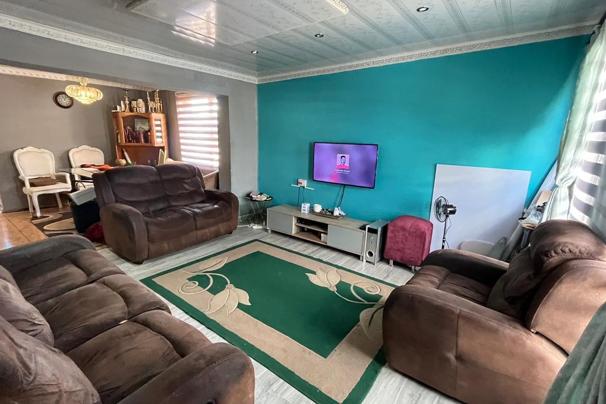 A living room featuring tiled flooring, recessed ceiling lighting, and decorative ceiling molding, providing a functional space for relaxation.
