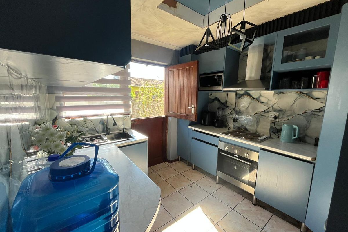 A kitchen featuring blue cabinetry, marble-effect splashbacks, and integrated appliances, requiring ceiling repairs to complete the space.