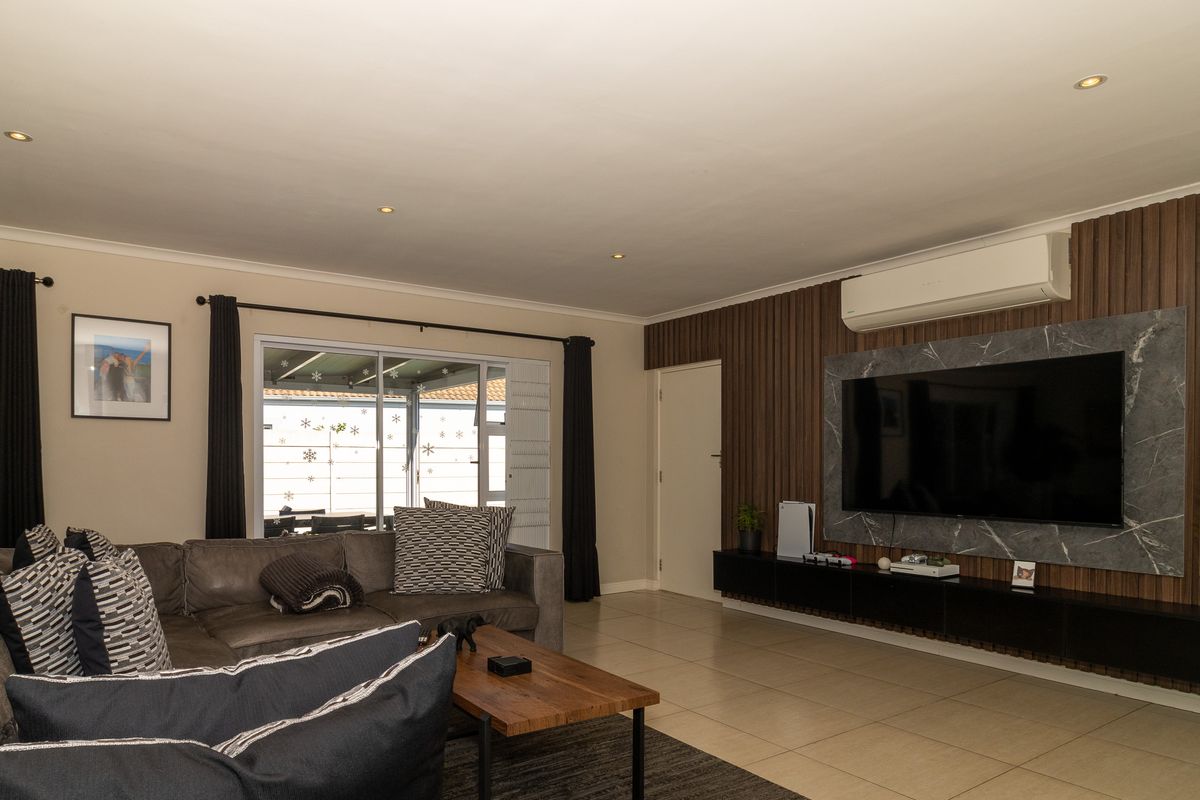 A modern living room featuring tiled floors, slatted wood wall paneling, a marble-effect media feature wall, and integrated air conditioning.