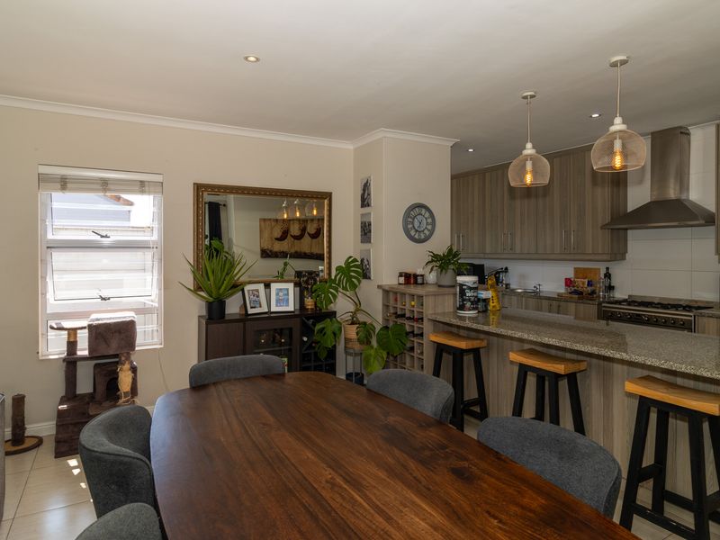 Open-plan living and dining area featuring a modern kitchen with granite countertops, built-in cabinetry, and a cozy wood-burning fireplace.