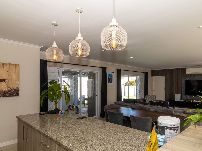 Spacious open-plan living area featuring a granite-topped kitchen island, modern pendant lighting, and sliding doors leading to the outdoor patio.