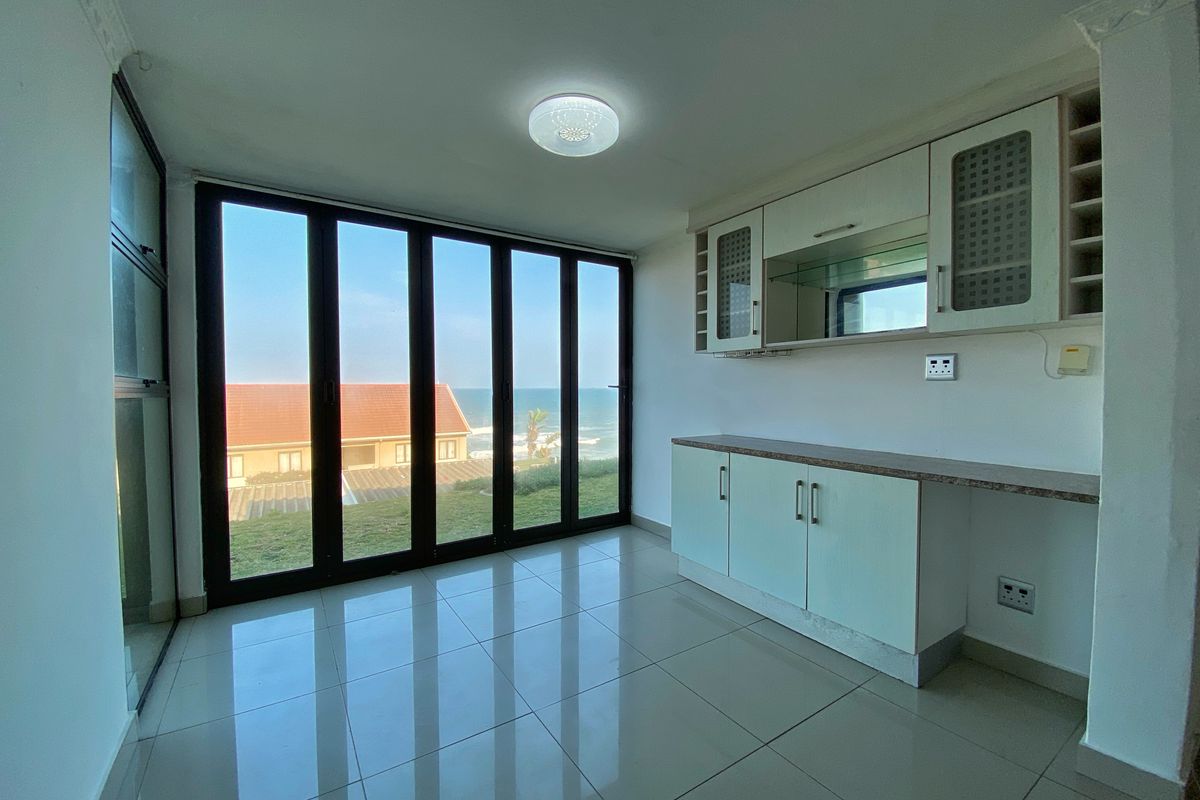 An empty living area featuring tiled floors, built-in cabinetry, and large glass doors offering scenic ocean views.