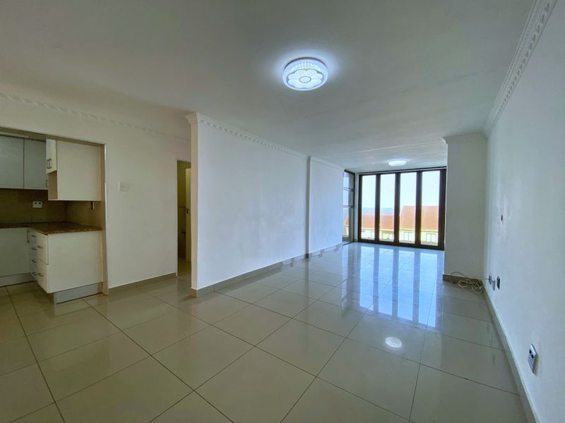 An open-plan living and kitchen area featuring tiled floors, built-in cabinetry, and large glass doors leading to an outdoor space.