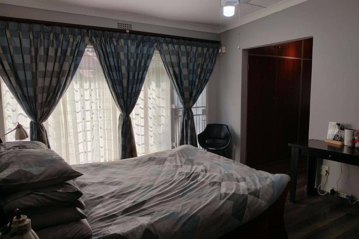 A bedroom featuring laminate flooring, a ceiling fan, and built-in cupboards, with access to an outdoor area through a sliding door.