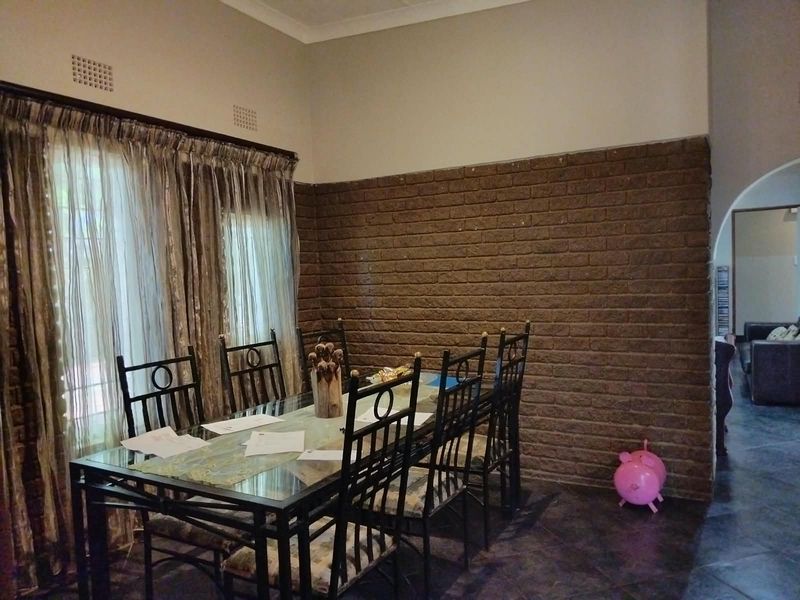 Dining room featuring an exposed brick accent wall, tiled flooring, and an arched entryway leading to the adjacent living space.