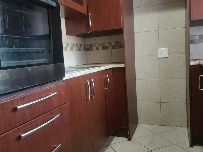 A functional kitchen featuring built-in cabinetry, a wall-mounted oven, laminate countertops, and tiled backsplash, offering a practical layout for culinary activities.