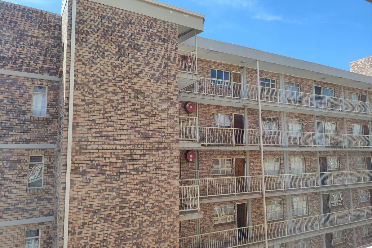 Exterior view of a multi-story apartment building featuring face brick facade, private balconies with metal railings, and visible fire safety equipment.