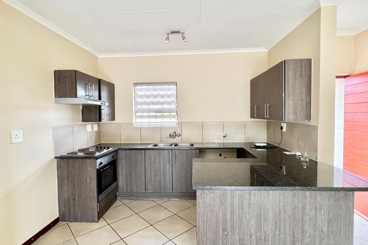 Modern kitchen featuring dark wood cabinetry, granite countertops, built-in oven and stove, and tiled flooring in a clean, functional layout.