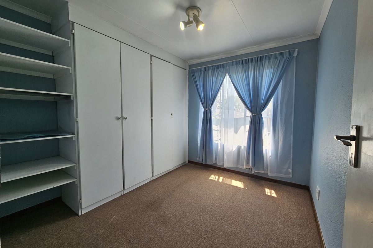 A vacant bedroom featuring built-in cupboards, open shelving, and carpet flooring, offering a functional space ready for personalization.