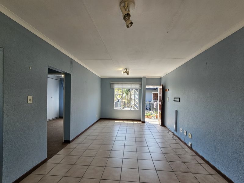 An empty living room featuring ceramic floor tiles, blue painted walls, and direct access to an outdoor balcony area.