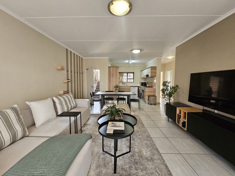 Spacious open-plan living and dining area featuring tiled flooring, neutral walls, and a functional kitchen with built-in cabinetry.