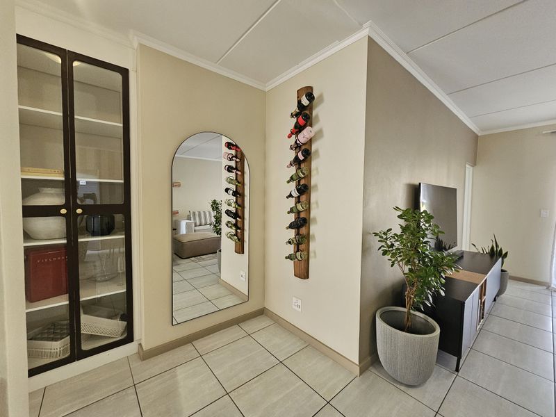A well-maintained living area featuring tiled flooring, a built-in display cabinet, and coved ceiling details, creating a clean and functional space.