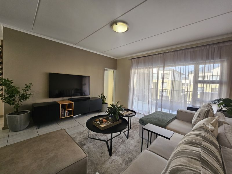 A well-lit living room featuring tiled flooring and a large sliding glass door that provides access to an outdoor balcony area.