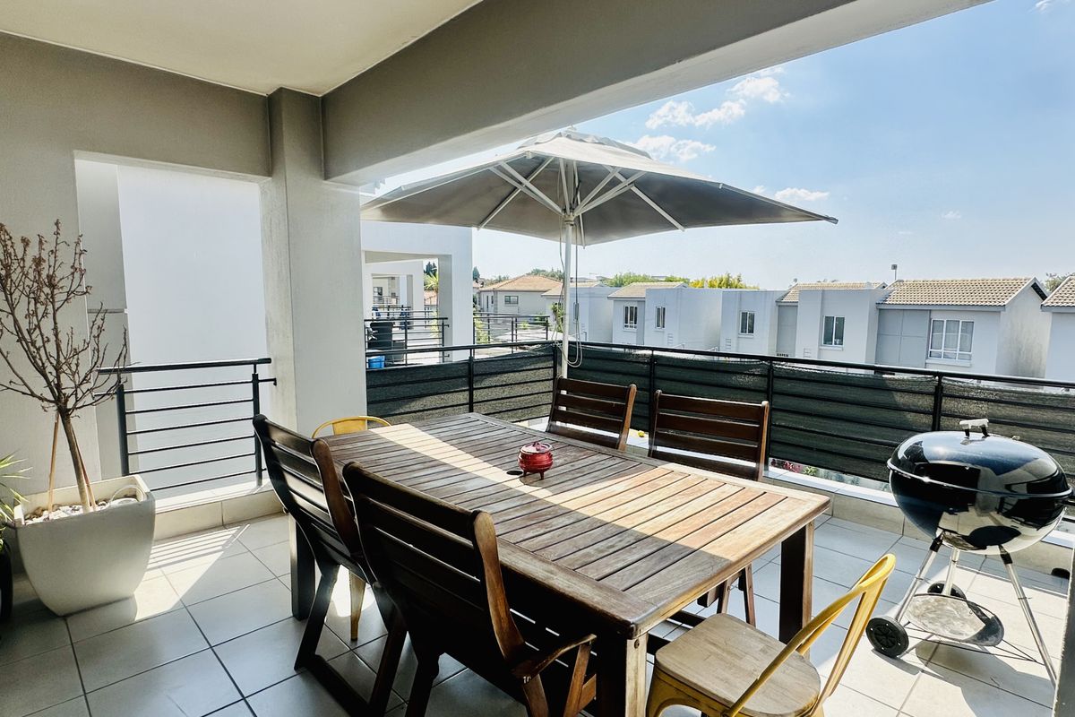 A spacious covered balcony featuring tiled flooring and metal balustrades, offering an ideal outdoor area for dining and relaxation.