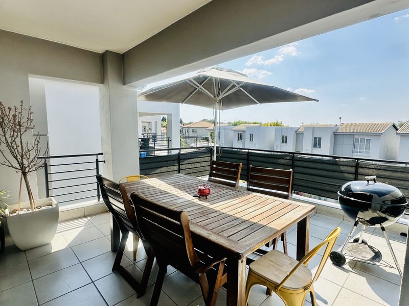 A spacious covered balcony featuring tiled flooring and metal balustrades, offering an ideal outdoor area for dining and relaxation.
