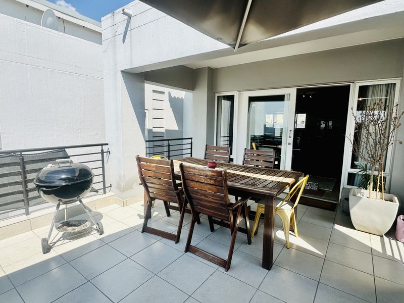 A covered outdoor patio featuring tiled flooring and sliding glass door access to the interior living space, ideal for alfresco dining.
