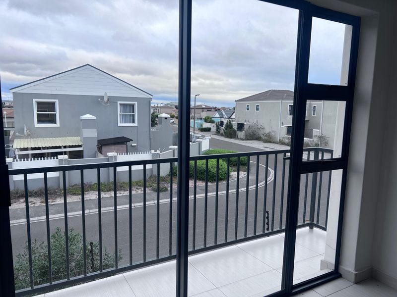 A clean, tiled balcony with a metal balustrade, offering an elevated view of the surrounding residential street and neighbouring properties.