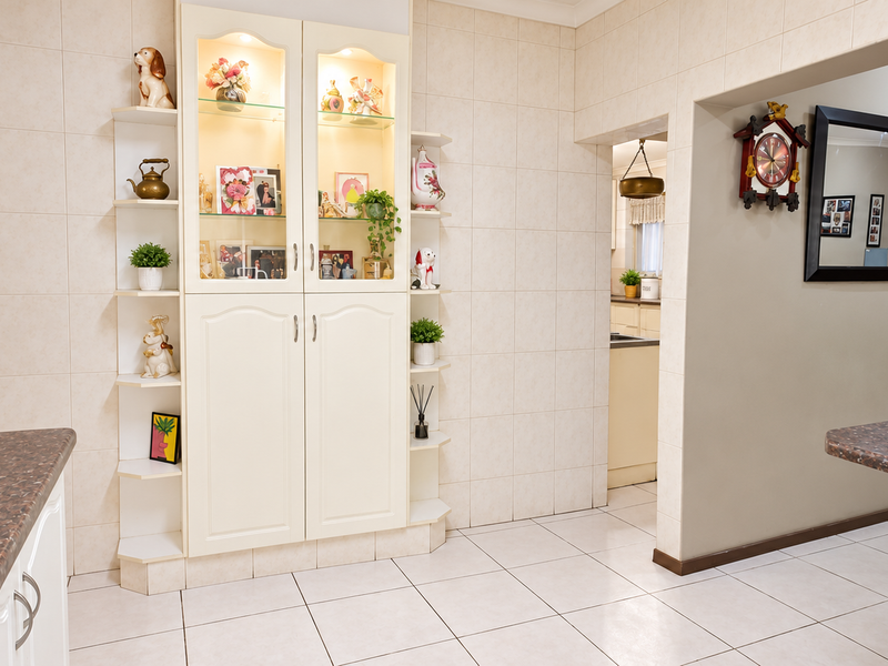 A functional kitchen area featuring built-in display cabinetry, tiled walls, and durable laminate countertops, providing a practical layout with access to adjacent spaces.