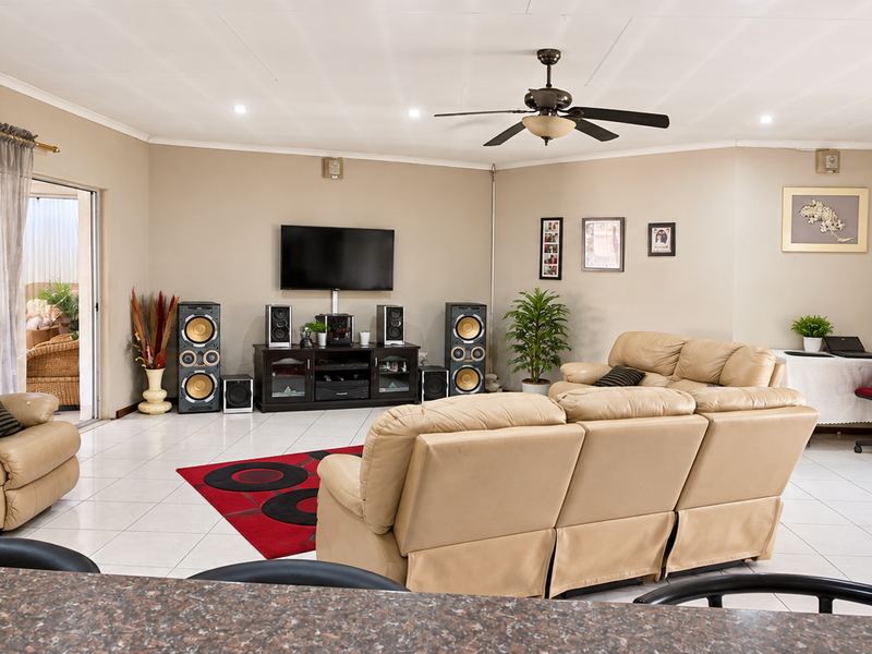 Spacious living room featuring tiled flooring, a ceiling fan, and sliding glass doors leading to an outdoor area.