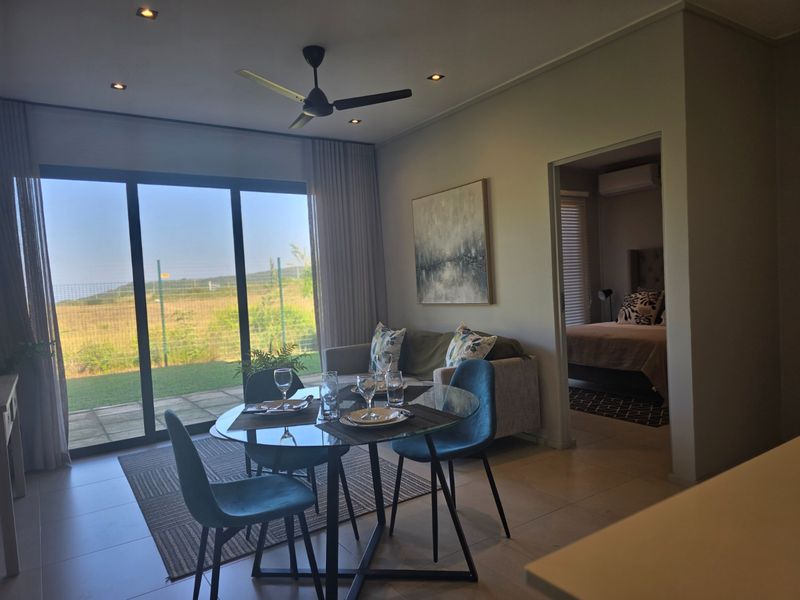 Open plan living and dining area featuring tiled floors, recessed lighting, and large sliding glass doors leading to an outdoor patio area.