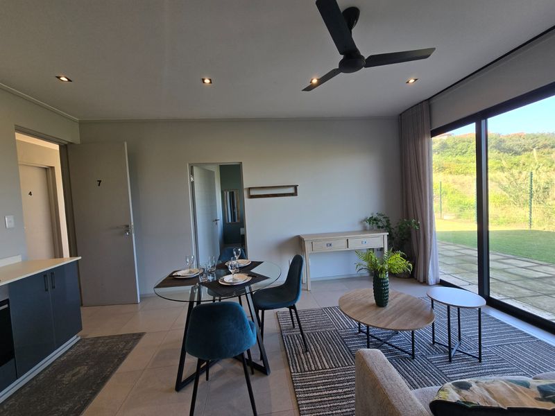 Modern open-plan living and dining area featuring tiled floors, recessed lighting, a ceiling fan, and large sliding glass doors leading to the garden.