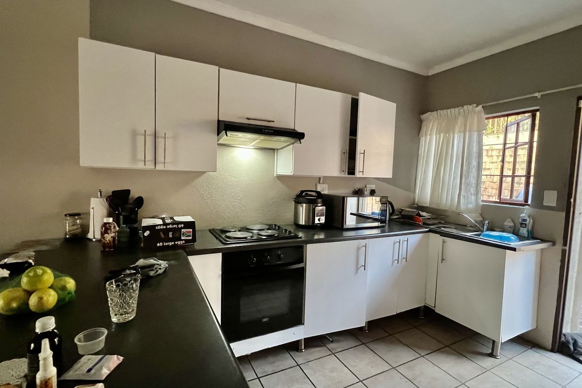A functional kitchen featuring white cabinetry, dark countertops, an integrated oven and hob, and tiled flooring with direct access to an outdoor area.