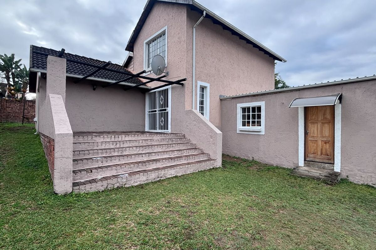 Rear exterior view of the house featuring a brick staircase leading to a patio area, timber door, and textured wall finish.