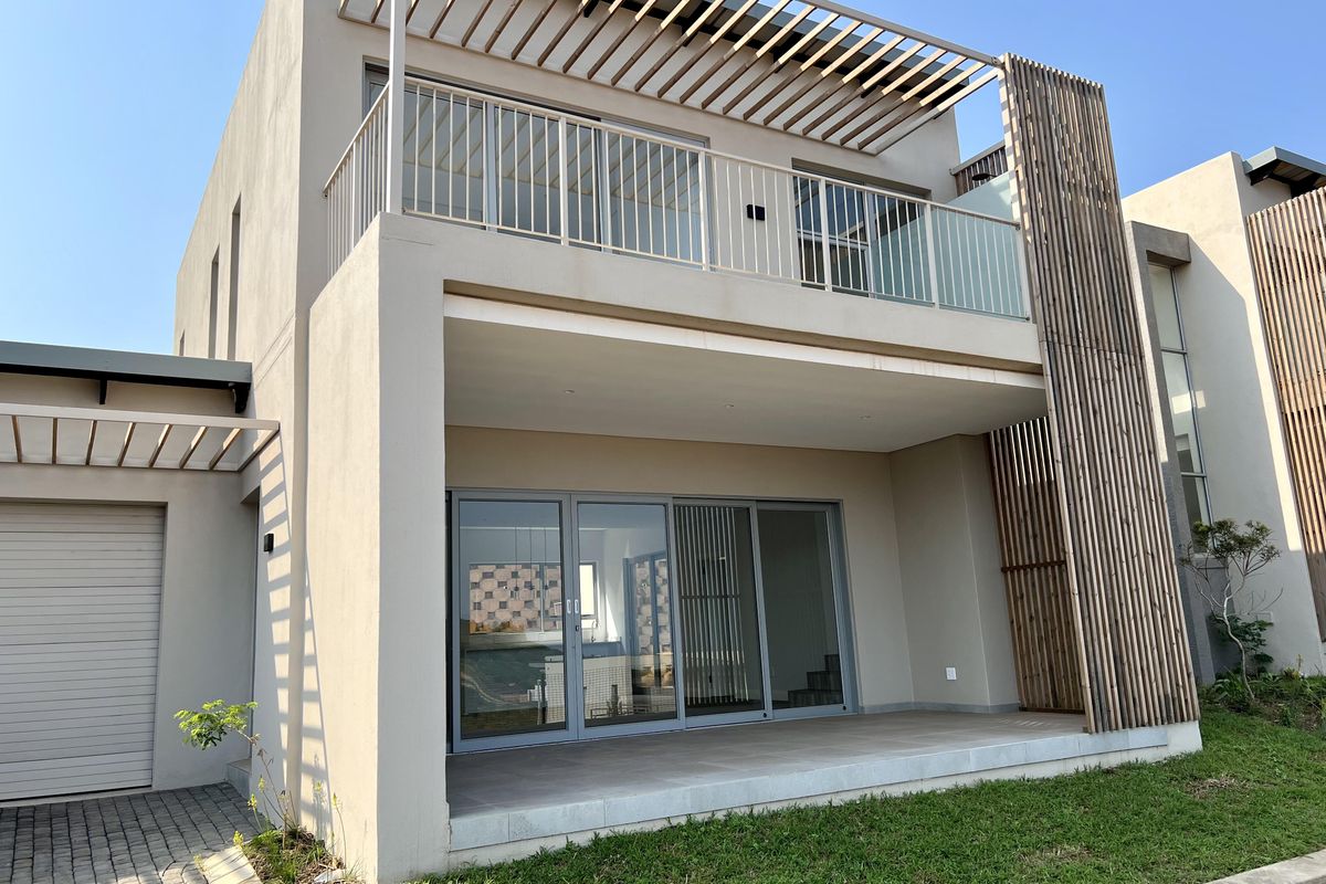 Modern double-story residence featuring a covered ground-floor patio, an upper-level balcony with timber pergola detailing, and integrated garage access.