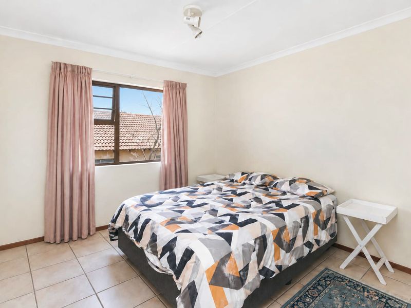 A functional bedroom featuring tiled flooring, a coved ceiling, and a window providing natural light.