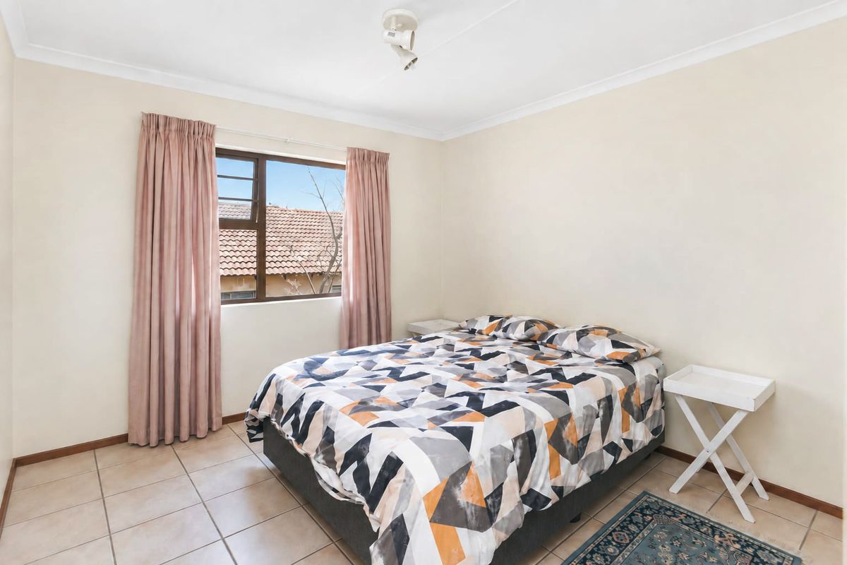 A functional bedroom featuring tiled flooring, a coved ceiling, and a window providing natural light.