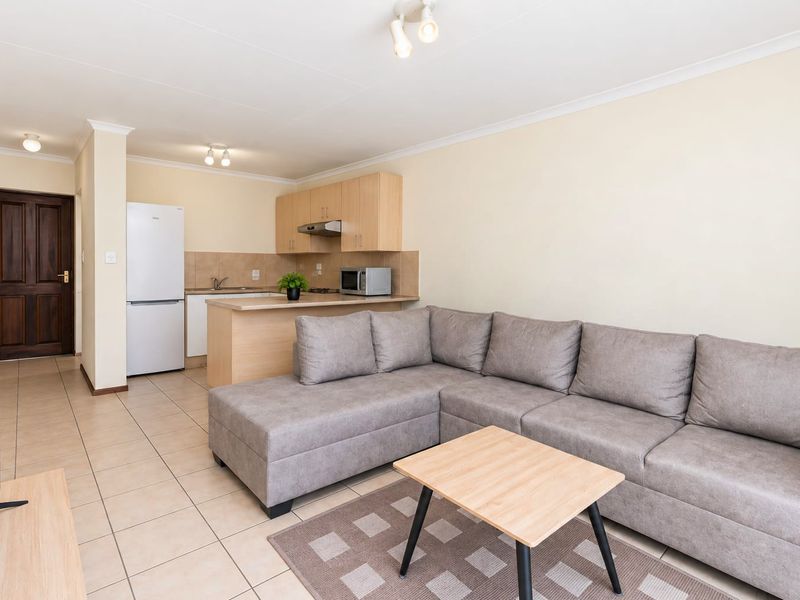 Open-plan living area featuring a functional kitchen with built-in cabinetry and tiled flooring throughout, creating a cohesive and practical living space.
