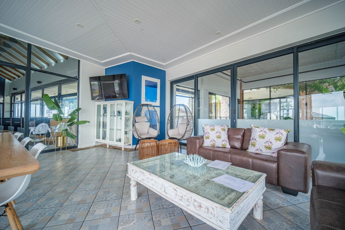 A bright and modern living area featuring tiled flooring, recessed ceiling lighting, and large aluminium-framed glass doors providing ample natural light.