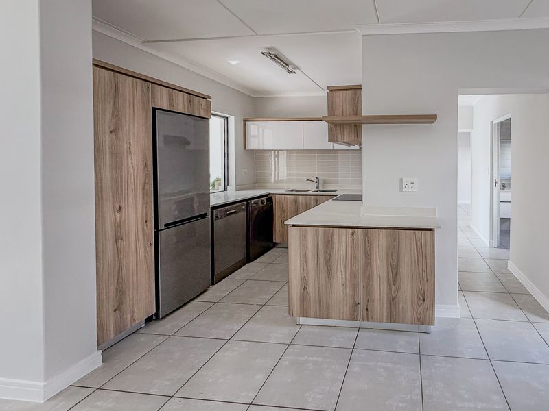 Modern kitchen featuring wood-grain cabinetry, stone countertops, tiled flooring, and integrated appliance spaces, offering a clean and functional culinary environment.