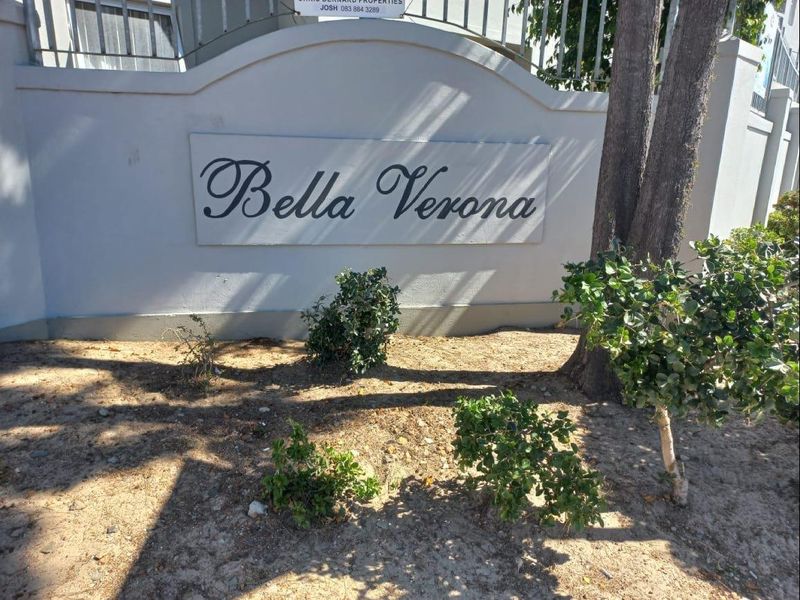 The entrance signage for the Bella Verona apartment complex, featuring a masonry boundary wall and established landscaping.