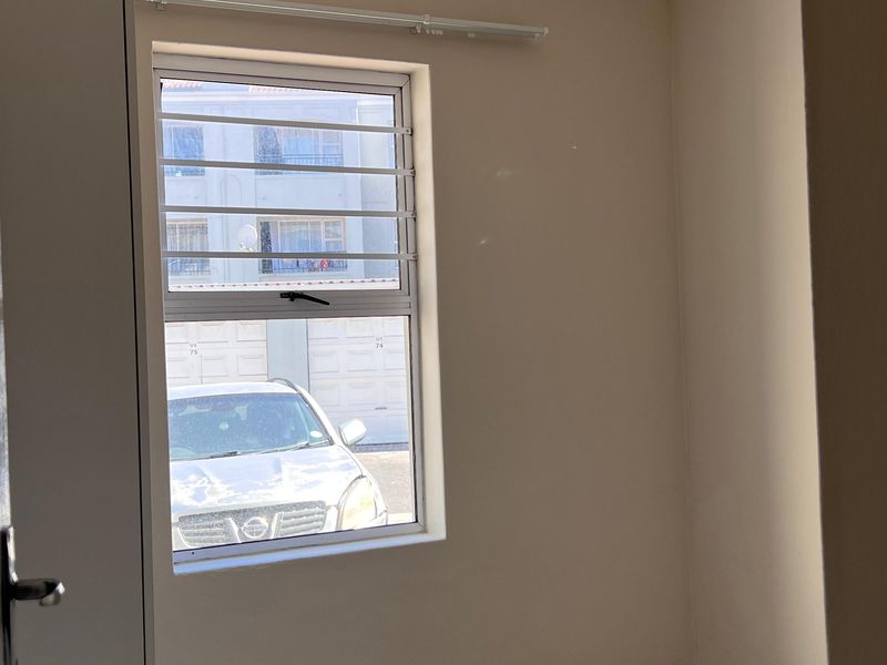 A vacant bedroom featuring neutral wall paint, tiled flooring, and a window fitted with security bars.