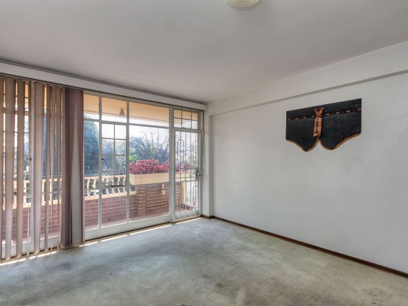 An empty living room featuring carpet flooring and a large sliding glass door providing access to an outdoor balcony area.