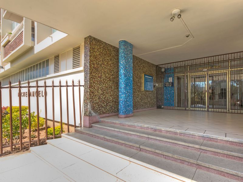 The apartment building entrance features a covered porch with tiled steps, a mosaic feature wall, and secure metal gate access.