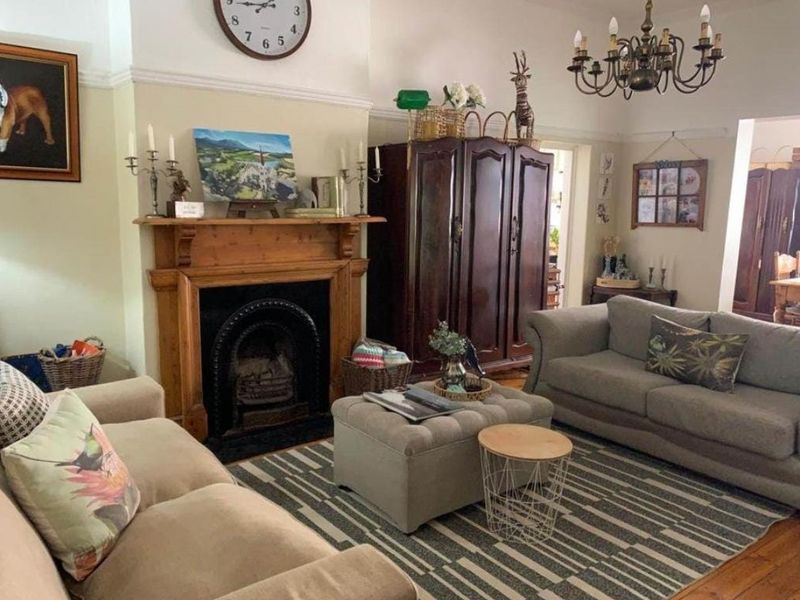 A classic living room featuring a traditional timber fireplace mantel, cast iron insert, hardwood flooring, and decorative crown molding.