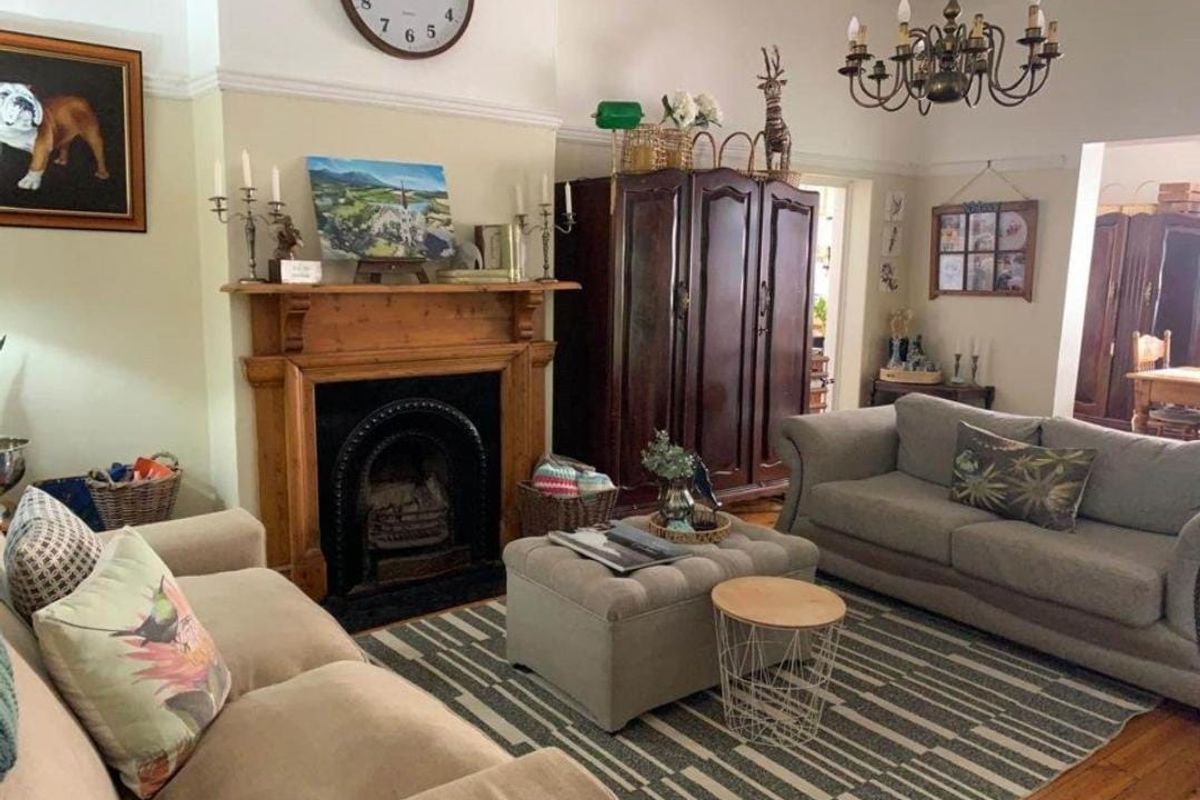 A classic living room featuring a traditional timber fireplace mantel, cast iron insert, hardwood flooring, and decorative crown molding.