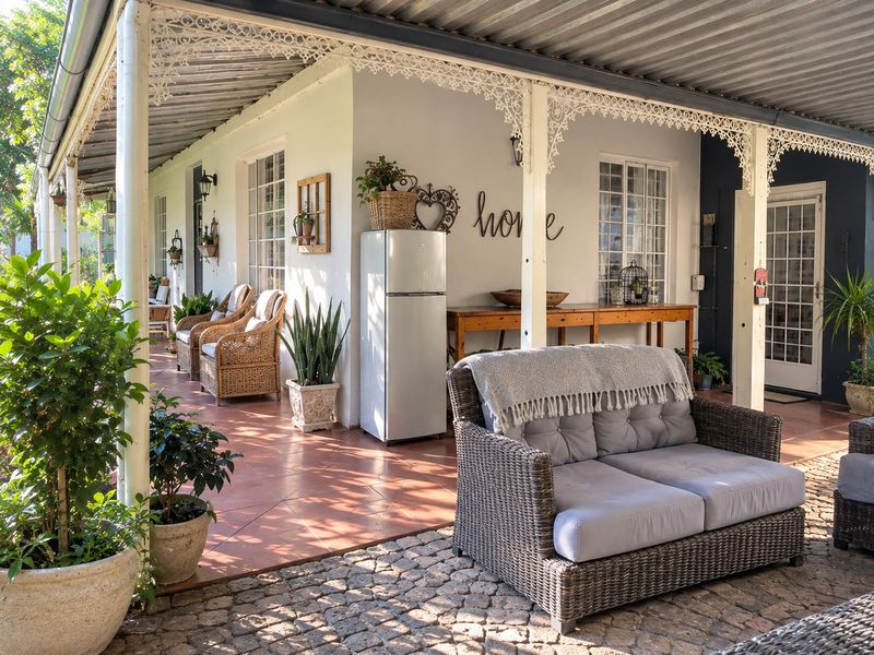 A spacious covered patio featuring decorative ironwork, tiled flooring, and direct access to the home through classic french doors.