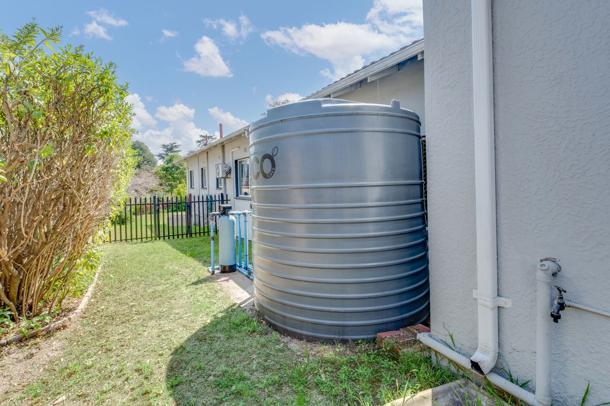 Side exterior view showing a large water storage tank, filtration system, and downpipe infrastructure along the side of the house.