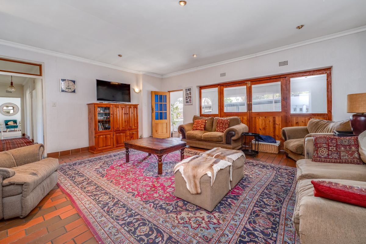 Spacious living room featuring terracotta tile flooring, wooden wall paneling, and recessed lighting, offering a comfortable and traditional living space.