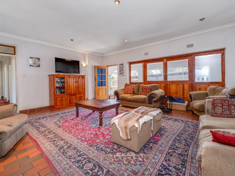 Spacious living room featuring terracotta tile flooring, wooden wall paneling, and recessed lighting, offering a comfortable and traditional living space.