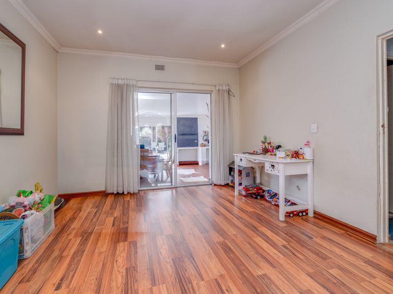 A bright living room featuring warm-toned laminate flooring, recessed lighting, and a sliding glass door providing access to the outdoor area.