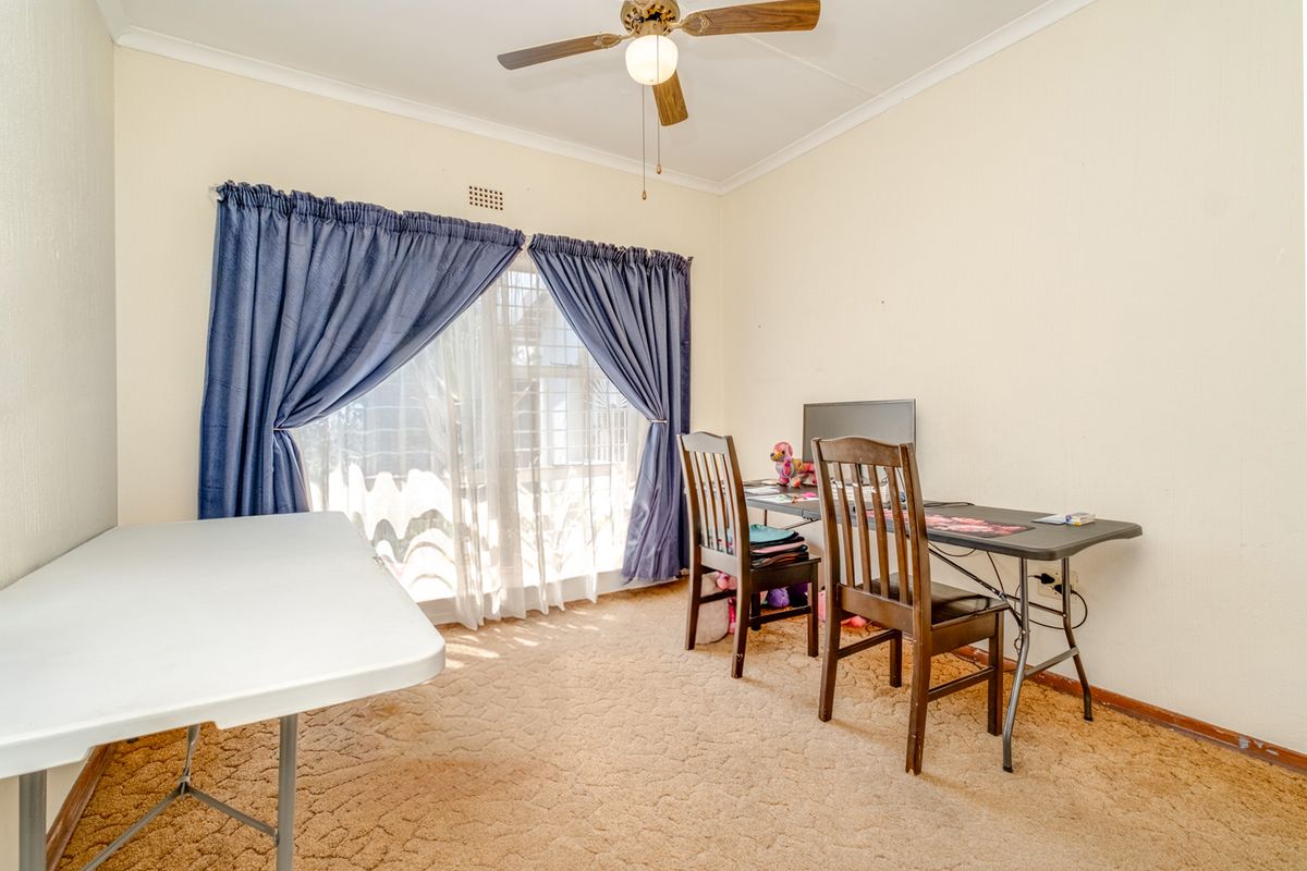 A bedroom featuring carpet flooring, a ceiling fan, and a sliding glass door providing natural light.