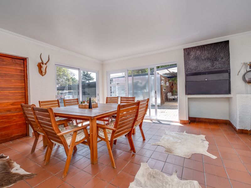 Covered patio area featuring tiled flooring, a built-in braai, and sliding glass doors providing access to the garden.