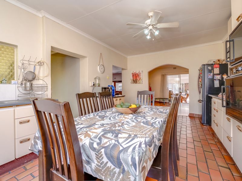 A functional kitchen and dining area featuring tiled flooring, built-in cabinetry, and an archway leading to the adjacent living space.