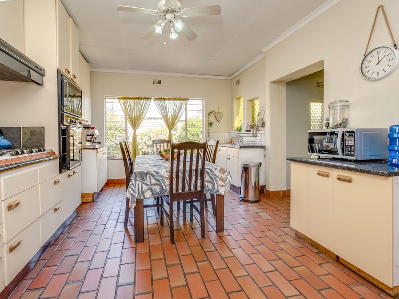 A functional kitchen featuring built-in cabinetry, integrated oven, hob, extractor fan, and durable tiled flooring, with an adjacent dining area.