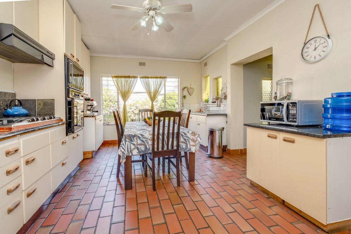 A functional kitchen featuring built-in cabinetry, integrated oven, hob, extractor fan, and durable tiled flooring, with an adjacent dining area.