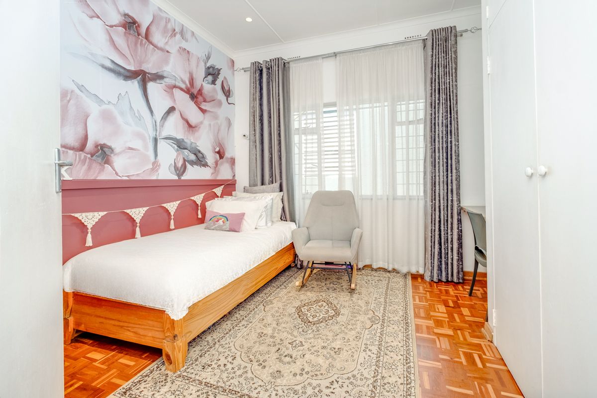A well-maintained bedroom featuring classic parquet flooring, a built-in cupboard, and recessed downlighting, creating a warm and inviting atmosphere.
